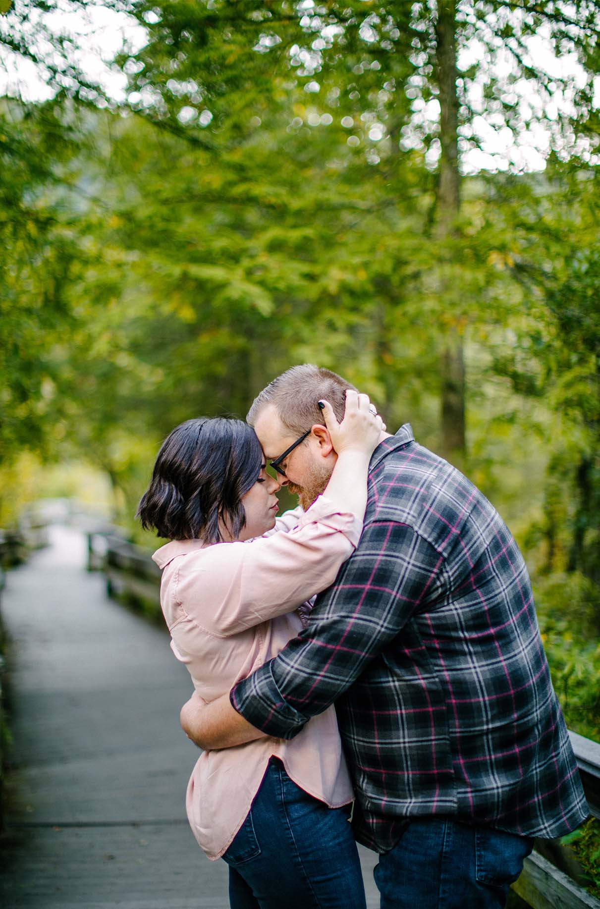 couple hugs with eyes closed on boardwalk during engagement session at labrador pond in tully ny