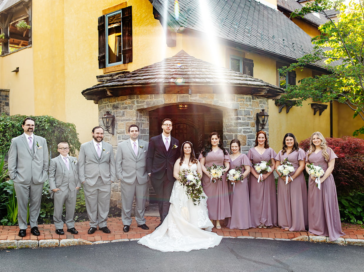 Wedding party stands together and smiles outside mirbeau inn spa in skaneateles ny