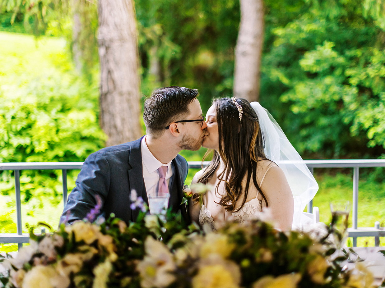 bride and grooms share a kiss at sweetheart table
