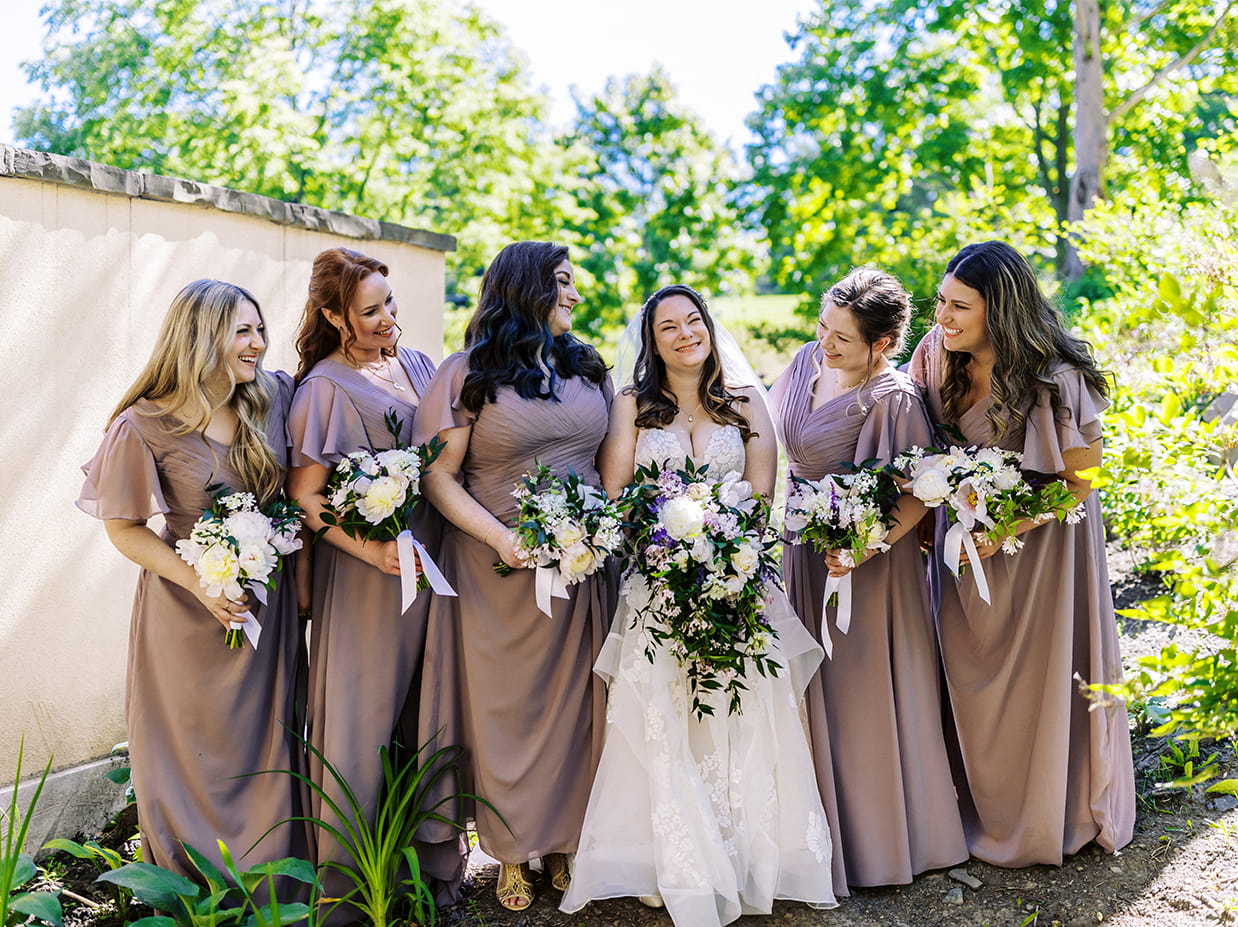 Bridesmaids stand with bride and laugh together at mirbeau inn and spa