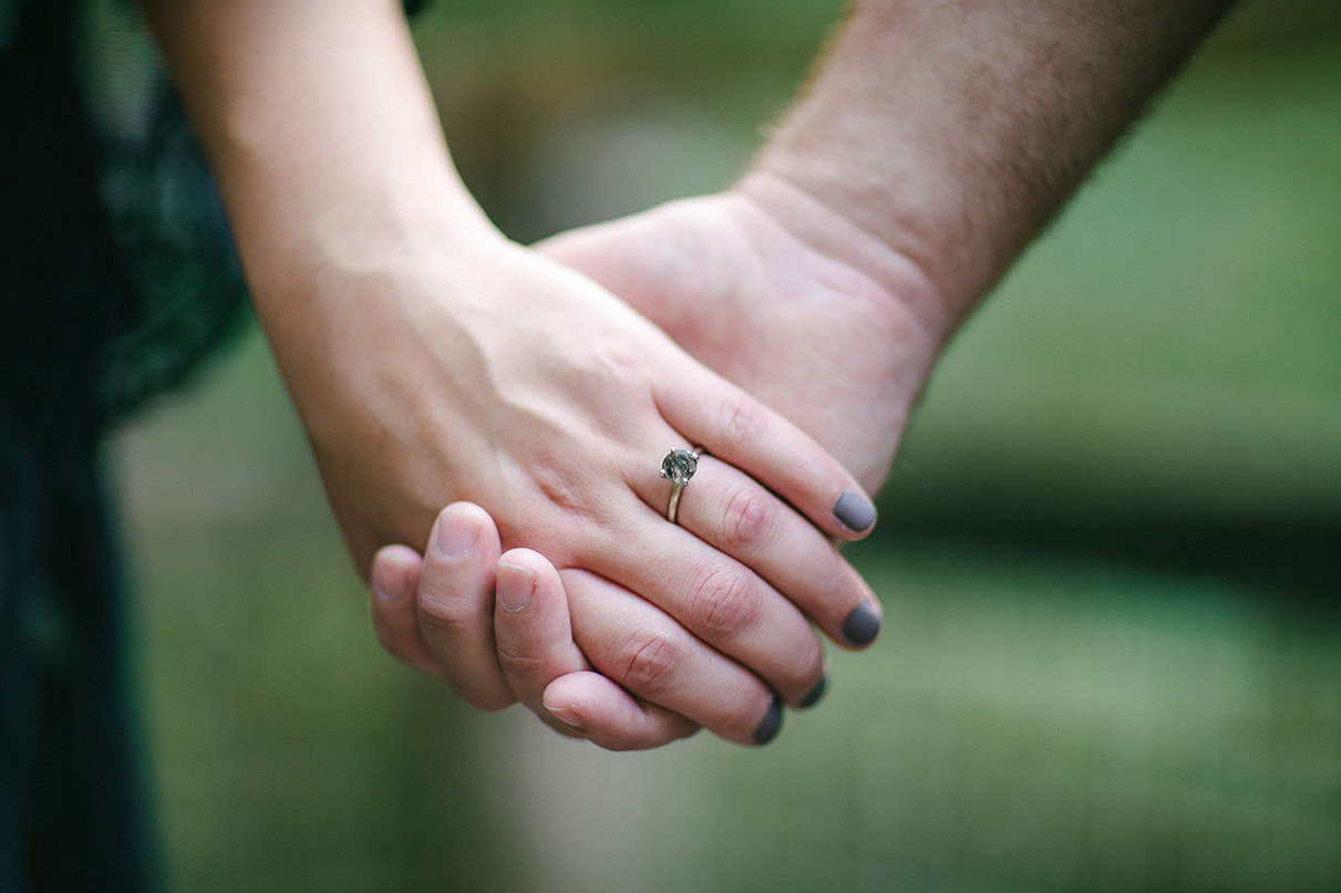 Man and woman holding hands with engagement ring on womans finger