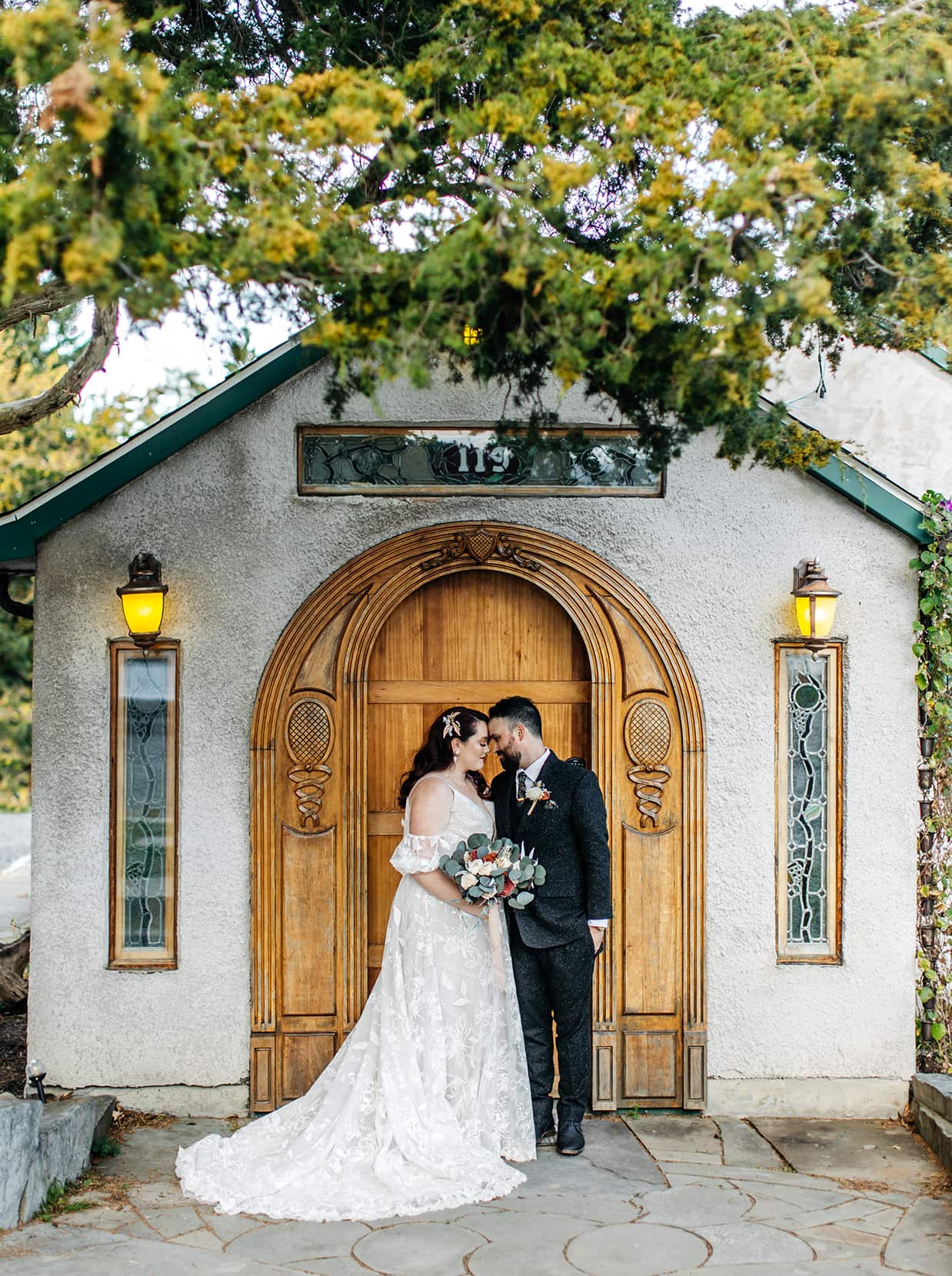 Bride and groom embrace in front of art-nouveau style carved door at their New Park Event Venue & Suites wedding in Ithaca NY