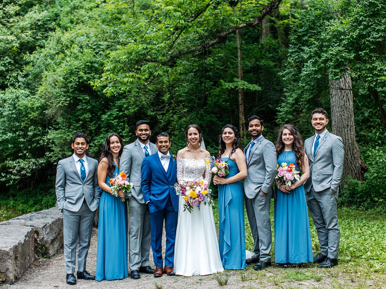 colorful bride, groom, and wedding party stands together and smiles