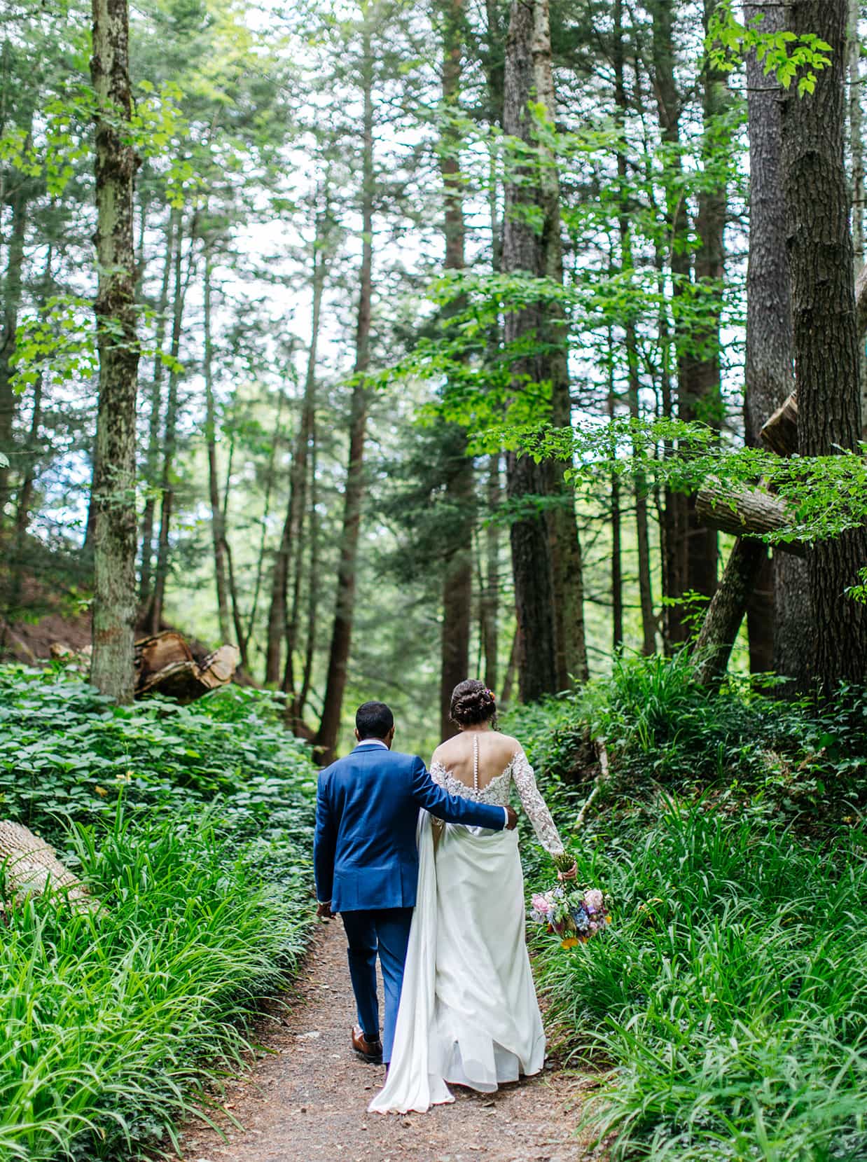 bride and groom walk together up forest path in Ithaca NY