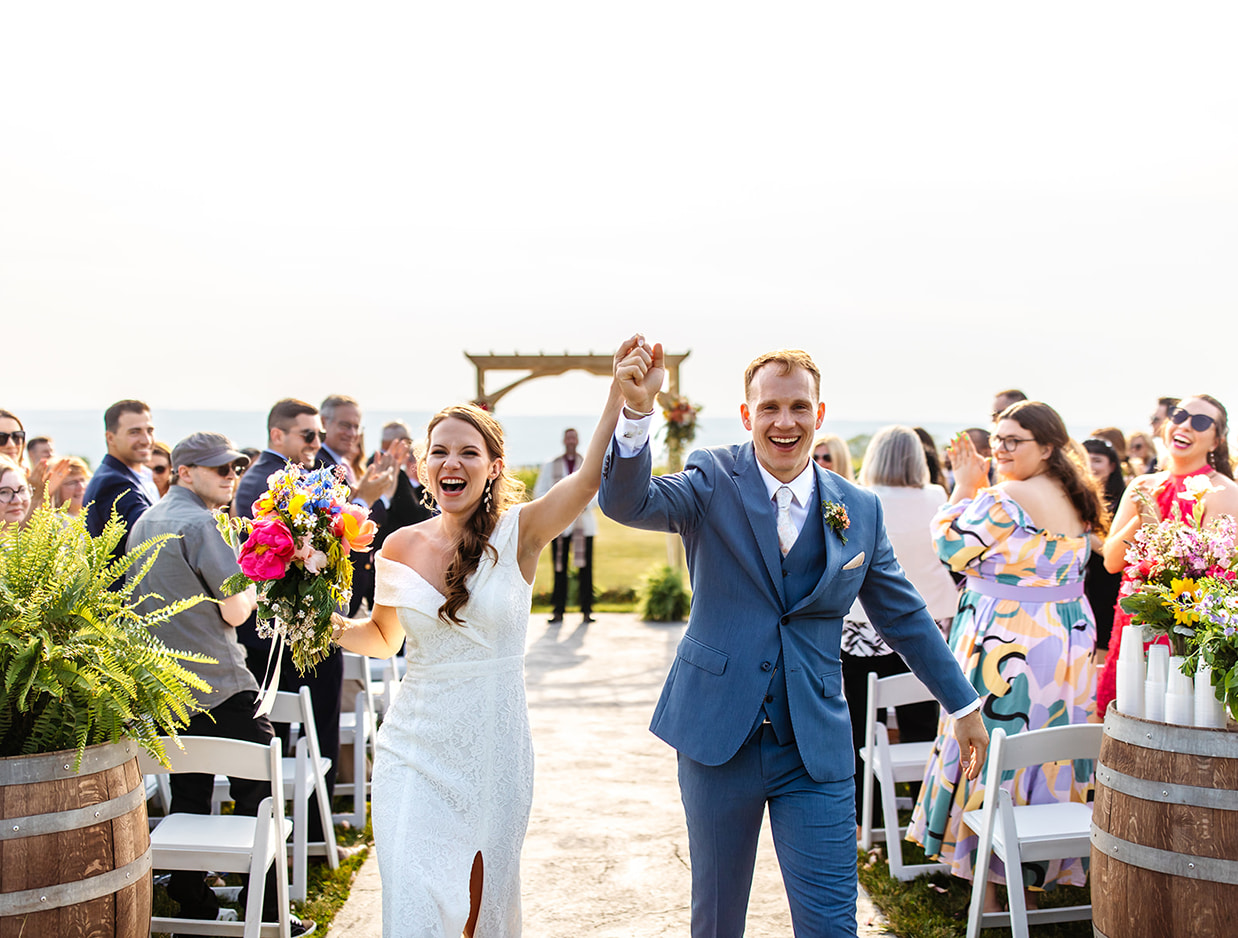 Bride and groom cheer while walking down the aisle after their wedding at The Ginny Lee Cafe at Wagner Vineyards in Lodi NY