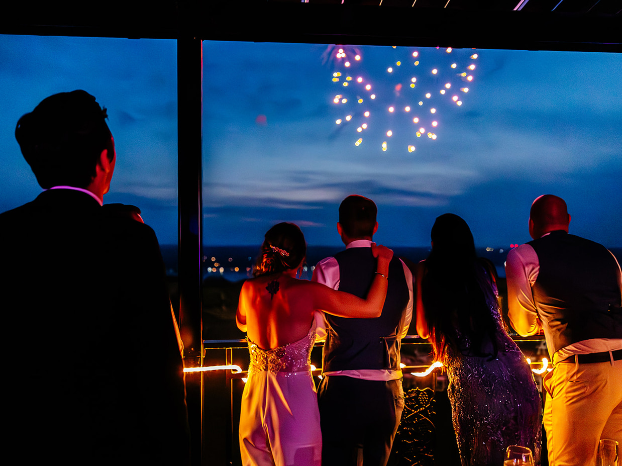 Bride and groom watch fireworks with their guests on the porch of The Ginny Lee Cafe at Wagner Vineyards in Lodi NY