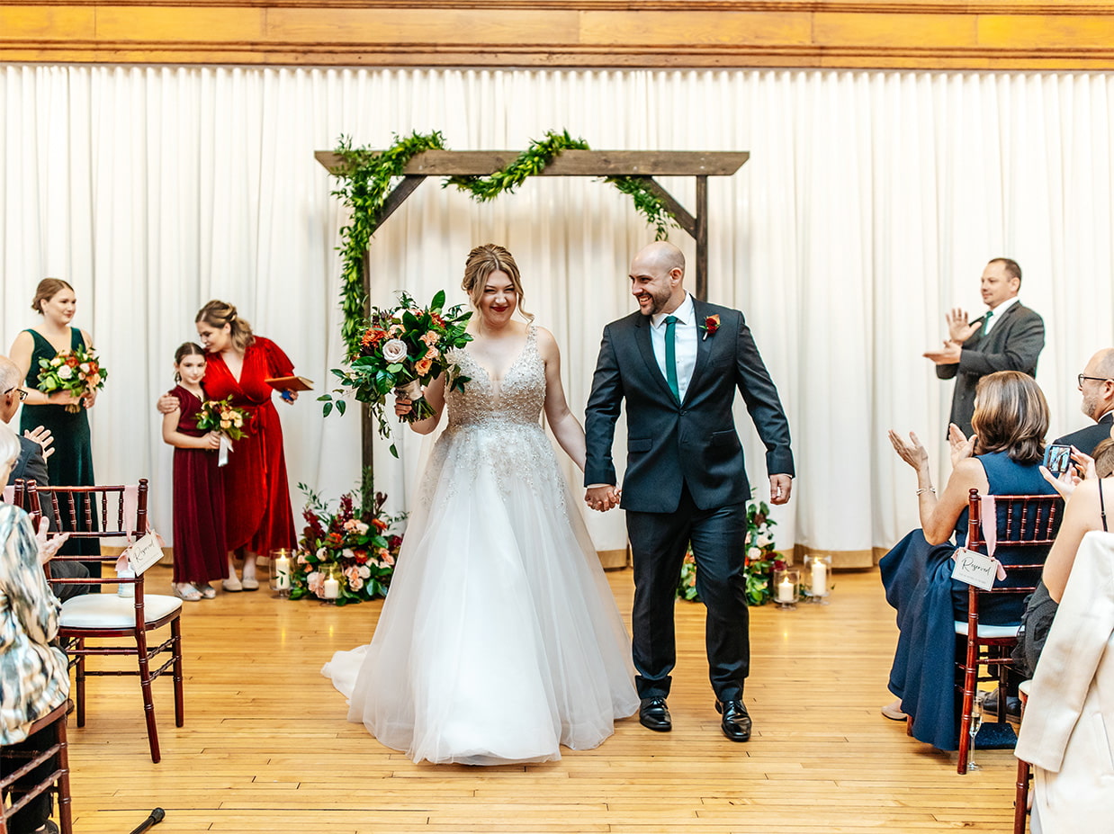 Bride and groom hold hands during precessional at The Historic German House in Rochester NY