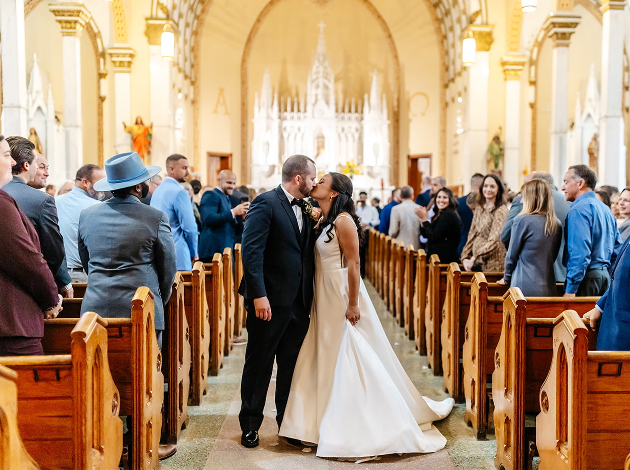 bride and groom share a kiss at the end of the aisle