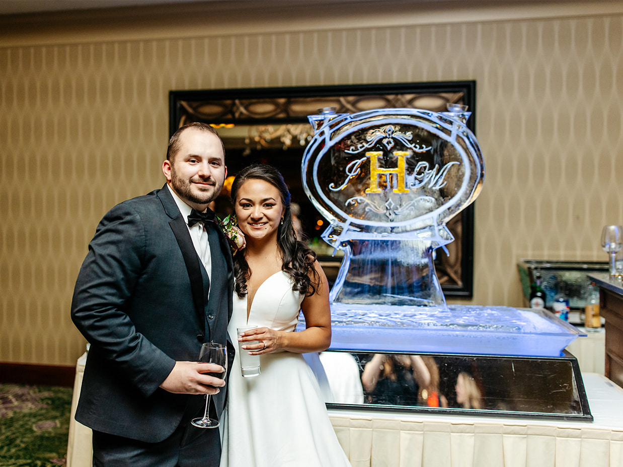 Bride and Groom smile in front of ice sculpture in the ballroom at Shenendoah Clubhouse