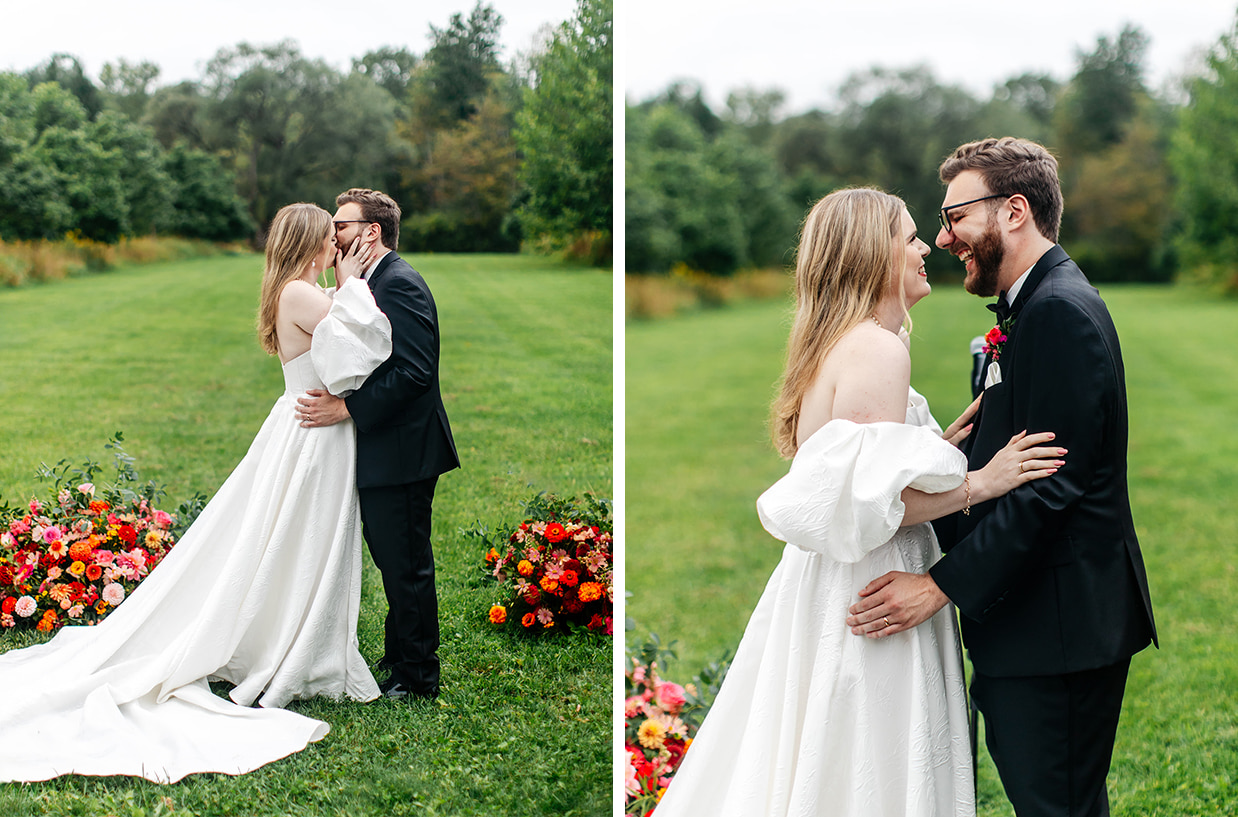 bride and groom share their first kiss in front of trees and pink, red, and orange flowers at the treman center in newfield NY