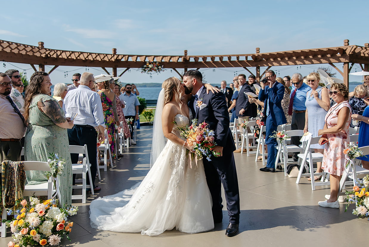 Waterfront wedding ceremony in the Thousand Islands with couple kissing by the St. Lawrence River