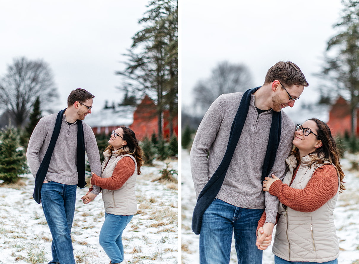 couple holds hands and walks playfully towards the camera during snowy upstate ny engagement session at a christmas tree farm
