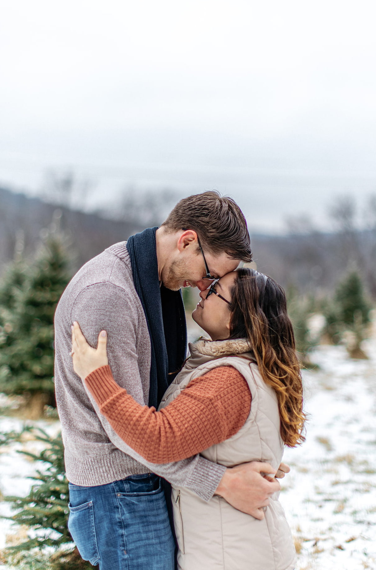 couple stands in field of christmas tree farm in binghamton ny with their foreheads together